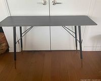Front view of charcoal black metal console table against white doors