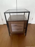 Front view of nightstand showing metal frame, open shelf, cabinet door