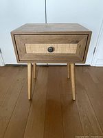 Full view of wood and wicker nightstand with legs visible