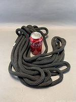 Full coil of black braided rope beside Coke can for scale