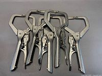 Five silver C-clamp pliers laid out
