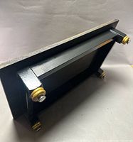 Underside view showing black painted frame and gold-tone feet