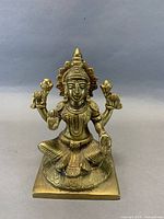 Front view of brass four-armed goddess figurine on square base