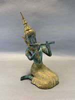 Front view of kneeling Thai musician sculpture with flute