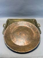 Round copper charger resting atop brass tray showing both items