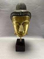 Front view of gilded wooden Buddha head on pedestal