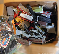 Top view of box showing mixed locomotive shells, freight cars, building parts, and bagged track