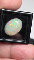 Front view of oval Ethiopian opal in display box showing multicolour pinfire pattern