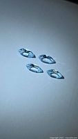 Four marquise-cut sky blue topaz gemstones on light background