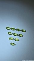 Ten oval peridots arranged on surface