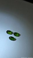 three oval green gemstones on neutral background
