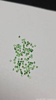 Group of small round green Tsavorite garnets scattered on white surface
