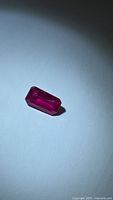 Emerald-cut vivid red ruby on white background, oblique view