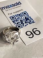 Ring beside lot tag showing heart-shaped quartz stone and silver band