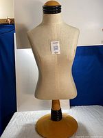 Front view of fabric-covered adjustable torso mannequin on circular base