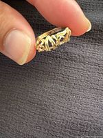 Oblique view of textured gold ring held between fingers