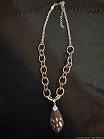 Full view of necklace showing chain of alternating silver and wood links with pendant attached