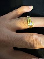 Ring on finger showing gold-tone finish, crossover design and square-cut stone