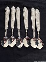 Front view of six matching teaspoons on black cloth