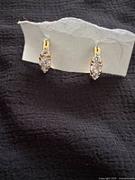 Front view of earrings on display card showing gold-tone finish and stone arrangement