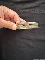 Pair of metal bangles held together, showing plain and patterned designs