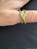 Ring worn on finger showing criss-cross gold and silver design