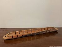 Full view of wooden baguette slicing board showing slots and overall shape