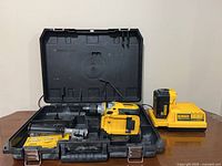 Open case showing drill, side handle, compartments; charger and battery alongside