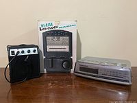 Group shot of all three items: mini amp speaker, boxed Sanyo clock radio, Panasonic RC-6266 clock radio