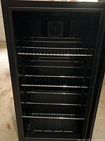 Front view of wine fridge showing shelving and interior