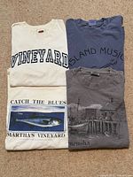 Four folded T-shirts showing front graphics