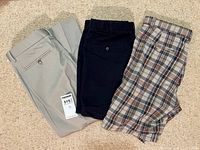 Overview of all three garments laid flat: khaki pants, navy shorts, plaid shorts