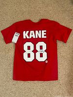 Full back view of red KANE 88 T-shirt showing size tag and autograph placement