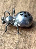 Front three-quarter view of sterling silver ladybug brooch showing body and legs