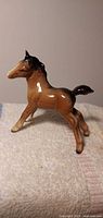 Left side view of brown Beswick foal figurine on cloth