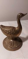 Front view of brass duck figurine on pedestal