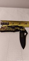 Knife open beside tape measure showing length