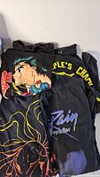 Stack of three graphic T-shirts showing main designs