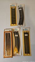 Five unopened packages of HO scale train track including four Bachmann blister packs and one Tyco box