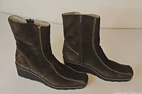 Side view of both boots showing suede, stitching, wedge heel