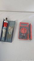 Both items side by side: screwdriver with bits pouch, multimeter in packaging