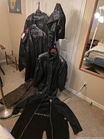 All three black leather outerwear items displayed together on hangers and laid out