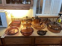 Overall lot showing amber pots, grill pan, rose dishes and large Dutch oven