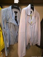 Front view of both powder blue and blush pink leather jackets on Danier hangers with tags