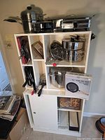 Overall lot on shelving showing pots, pans, lids, boxed cookware, utensils