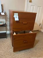 Front view of cabinet with top drawer closed, bottom drawer open showing wood grain and pull style