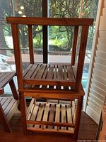 Two matching teak two-tier tables stacked for photo