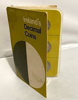 Front view of booklet standing, showing title and coin edges