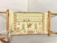 Sampler on wooden scroll frame with floss bag visible