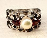 Front view of sterling ring showing garnets, pearl, and scroll design